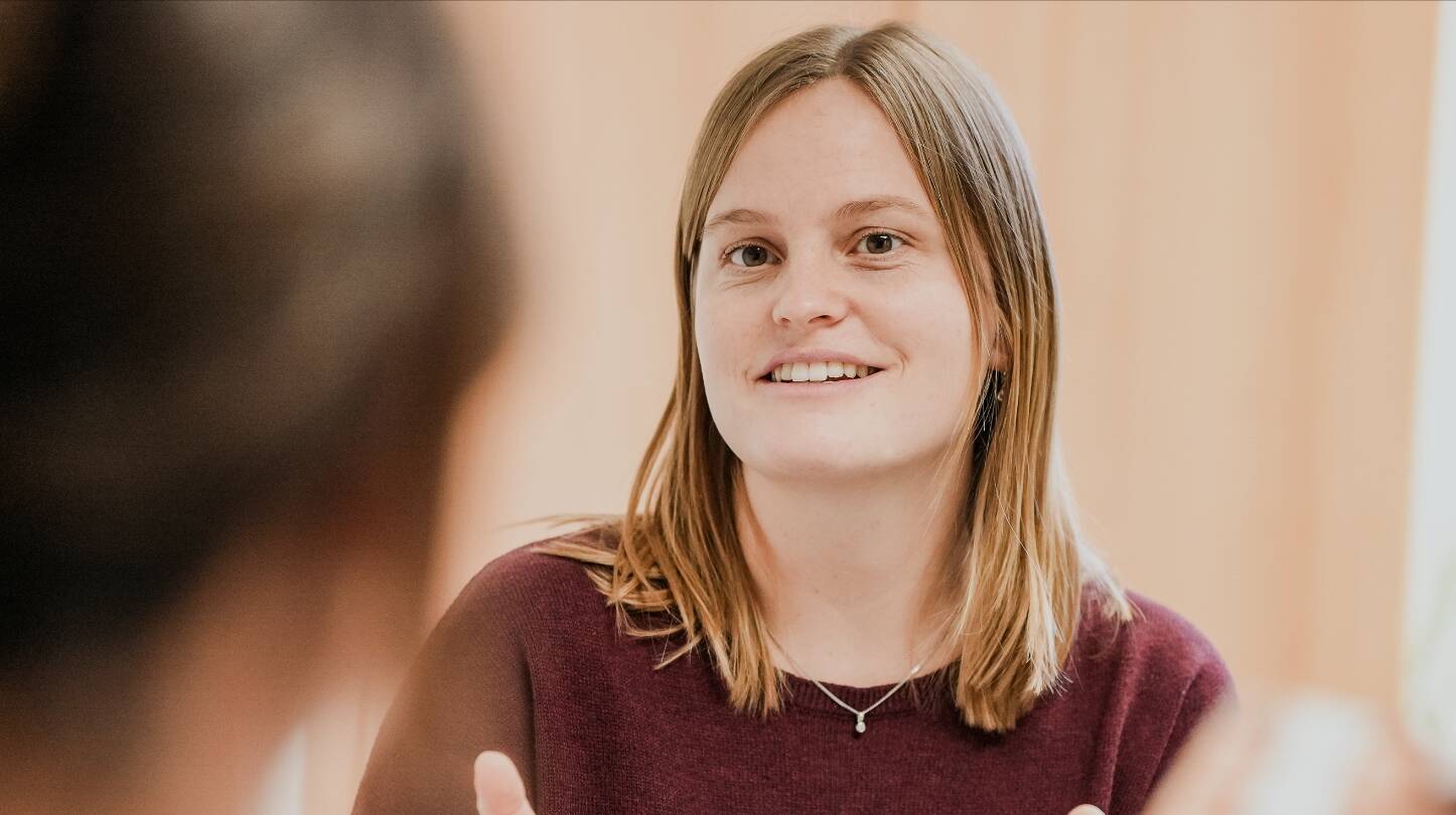 Junge Frau erklärt einer Person etwas